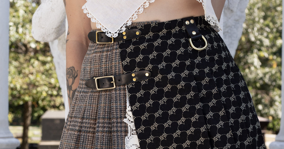 Person wearing a layered skirt with plaid, patterned, and lace designs outdoors.